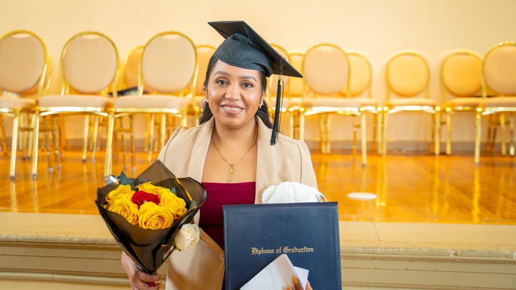 South Center graduate holding flowers and a diploma