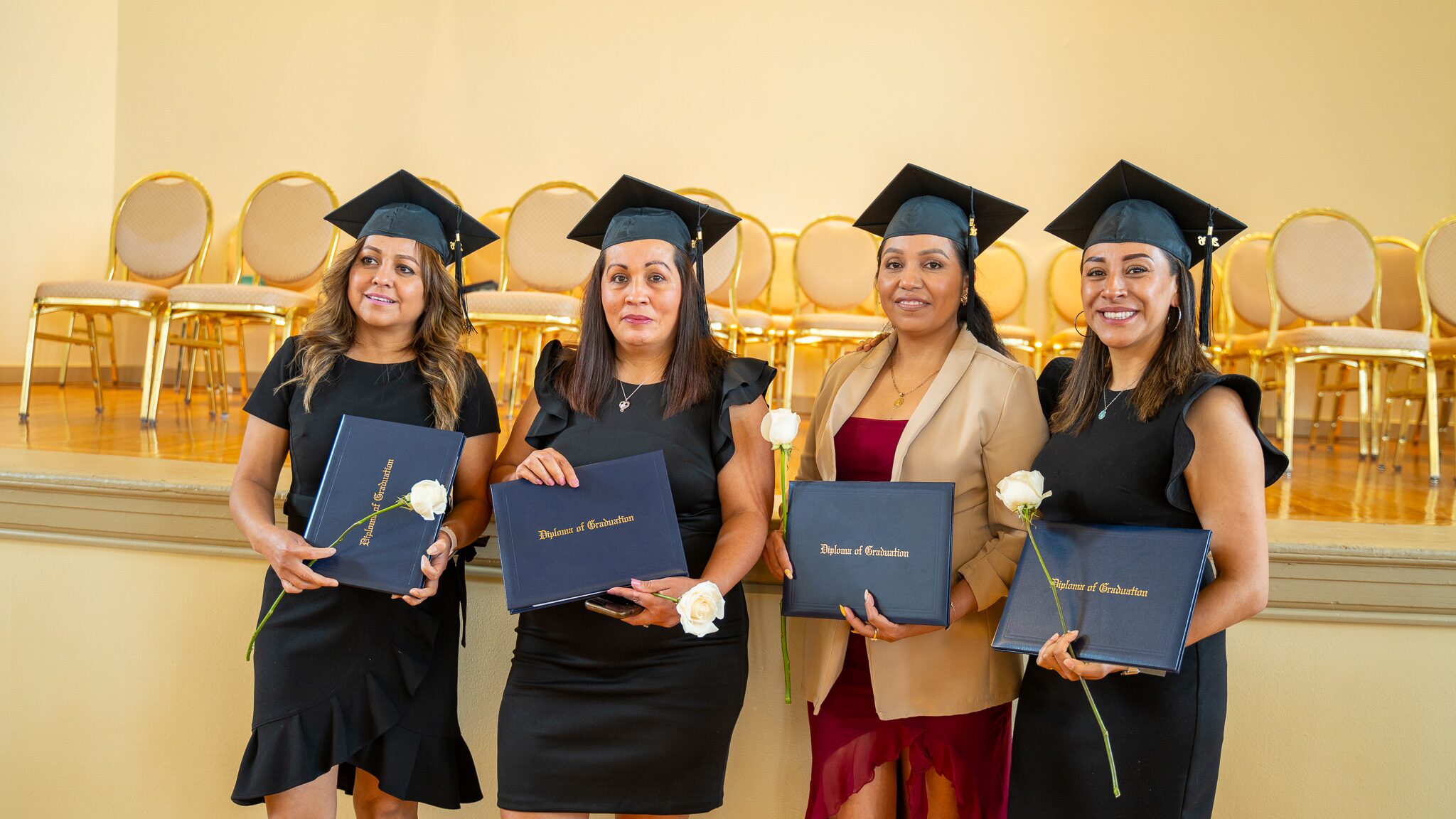Four South Center graduates in caps holding diplomas